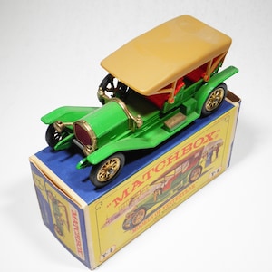 May include: A green toy car with a tan roof and gold wheels. The car is in its original Matchbox box, which is blue and yellow with the text "Matchbox" and "Models of Yesteryear".