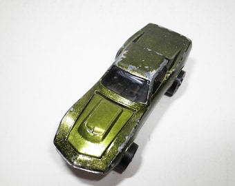 May include: A green toy car with a black interior and black wheels. The car has a slightly weathered look.