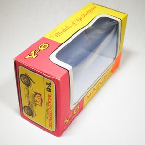 May include: A red and yellow Matchbox toy car box with a clear plastic window showing a 1913 Cadillac. The box has the text "Y-6" and "Matchbox" on it.