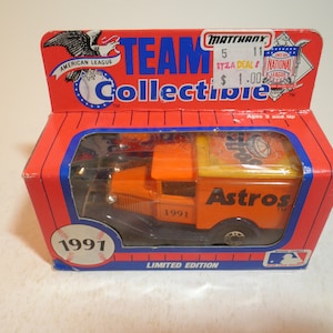May include: A 1991 limited edition toy delivery truck with the Houston Astros logo. The truck is orange and yellow with a black chassis. The box is red and blue with the words "Team Collectible" and "1991" printed on it.