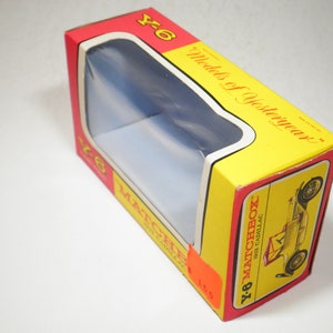 May include: A yellow and red cardboard box with a clear plastic window showing a toy car. The box has the text "Y-6 Matchbox Models of Yesteryear" and "1913 Cadillac" printed on it.