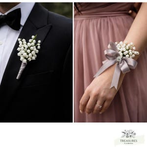 May include: A black tuxedo jacket with a white shirt and a black bow tie. A white flower boutonniere with a gray ribbon is pinned to the lapel. A wrist corsage with white flowers and a gray ribbon is also shown.