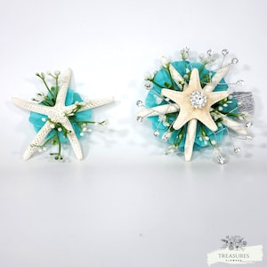May include: Two white starfish with turquoise blue tissue paper and white flowers. The starfish are arranged in a circular shape.