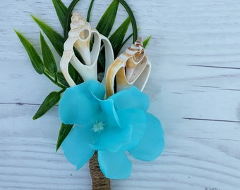 May include: A blue flower with a brown twine stem and two seashells. The seashells are white and brown with a natural texture.
