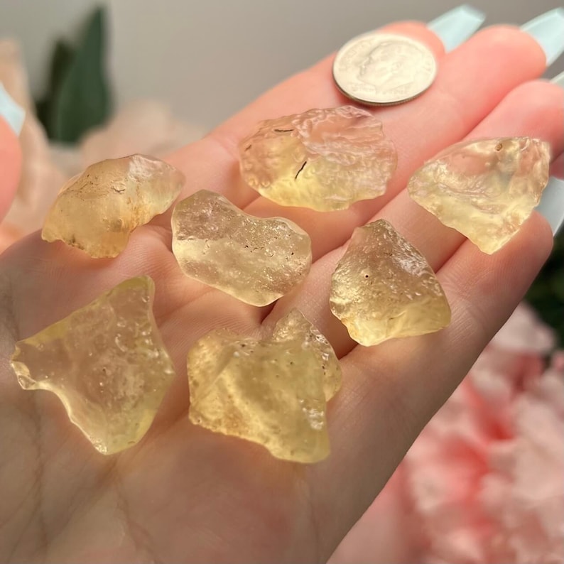 Puede incluir: Una colecci&oacute;n de cristales de citrino en bruto, de color amarillo dorado, cada uno con una forma y textura &uacute;nicas. Se incluye una moneda para comparar el tama&ntilde;o, mostrando las piedras preciosas naturales sin pulir.