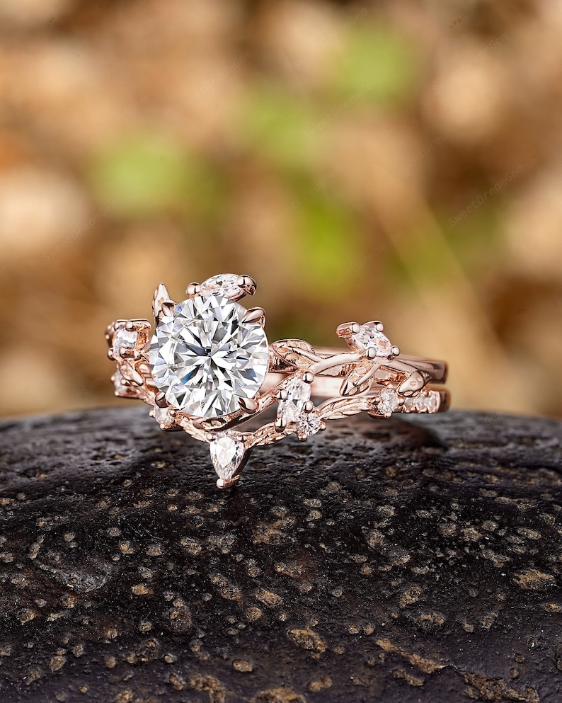 May include: A rose gold engagement ring with a large round center stone and smaller stones set in a delicate vine design.