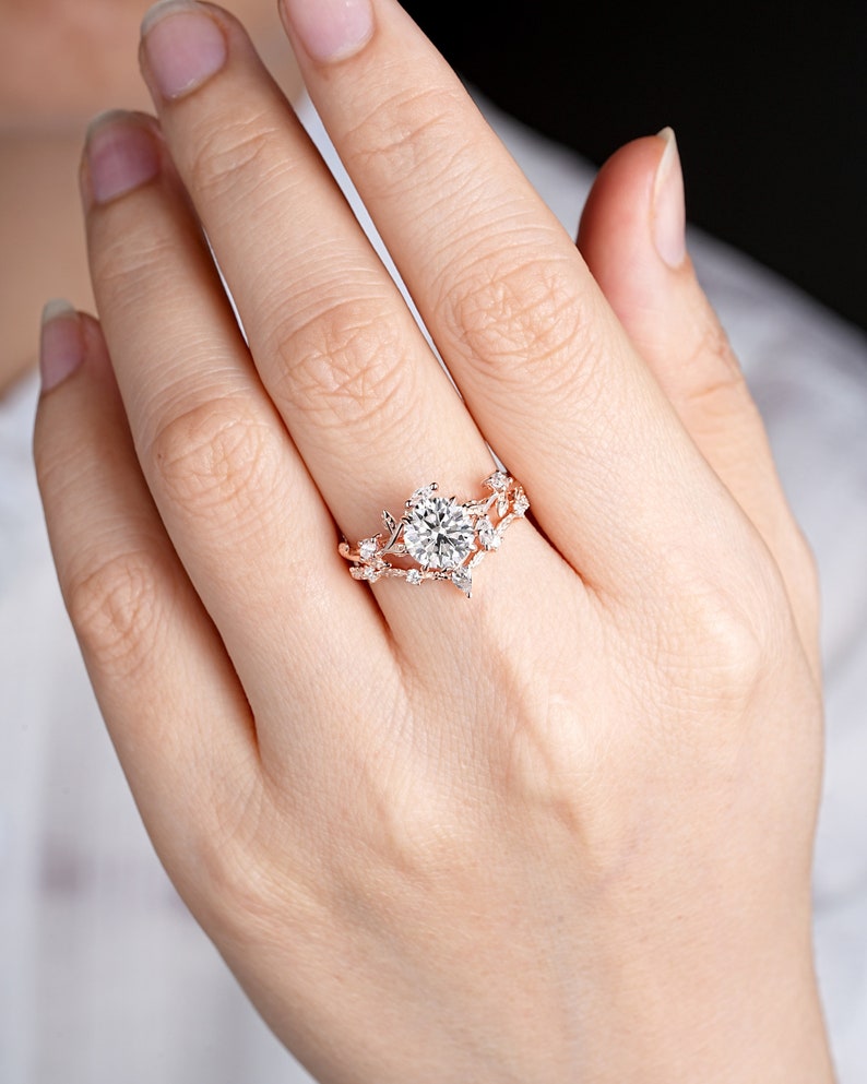 May include: A rose gold engagement ring with a large round center stone and smaller stones set in a delicate floral design.