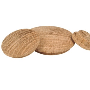 Könnte beinhalten: Drei runde Holzstopfen in verschiedenen Größen. Die Stopfen sind aus hellbraunem Holz mit einer Maserung.