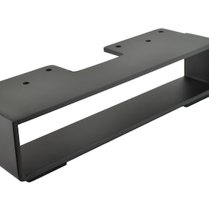 May include: A black metal bracket with a rectangular design. It features a top section with pre-drilled holes and a lower shelf-like structure. The bracket is designed for mounting and support.