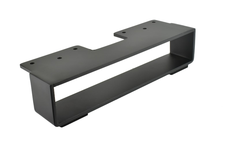 May include: A black metal bracket with a rectangular design. It features a top section with pre-drilled holes and a lower shelf-like structure. The bracket is designed for mounting and support.