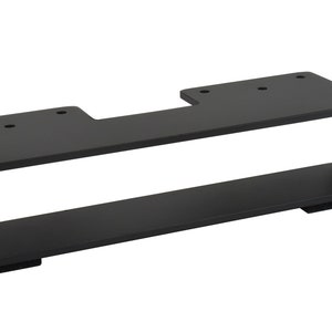 May include: A black metal bracket with a rectangular design. The bracket has a flat top with pre-drilled holes and a lower shelf. The overall shape is a long rectangle with an open center.