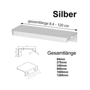 Può includere: Maniglia per armadio in argento con bordo arrotondato e un'incisione. La maniglia è disponibile in lunghezze che vanno da 8,4 a 120 cm. La maniglia è mostrata in un disegno a linea con misure in centimetri.