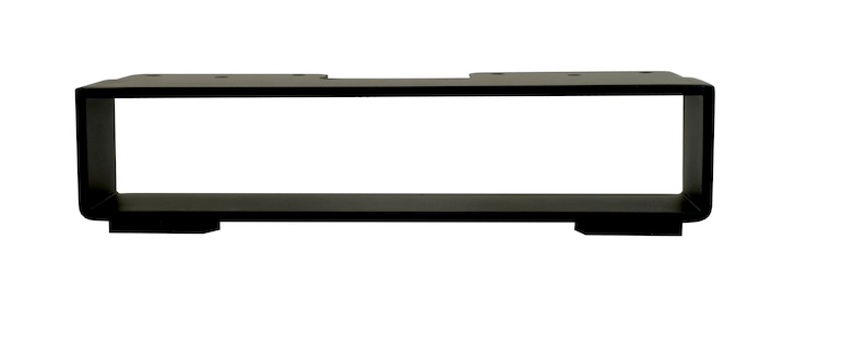 May include: A black, rectangular shelf bracket with a minimalist design. The bracket has a hollow center and is supported by two small feet. The top of the bracket has pre-drilled holes for mounting. The bracket is made of metal and has a matte finish.