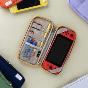 May include: A yellow, orange, blue, and white zippered carrying case for a Nintendo Switch console. The case has multiple compartments for game cartridges, a stylus, and other accessories. The case is open and a red Nintendo Switch console is inside.