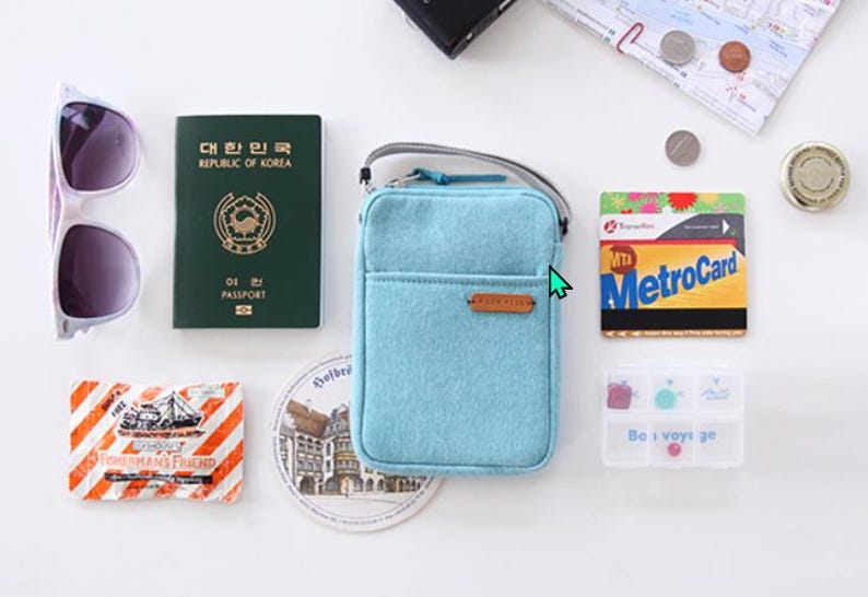 Puede incluir: Una colecci&oacute;n de elementos esenciales de viaje que incluyen un bolso cruzado azul claro, gafas de sol, un pasaporte de la Rep&uacute;blica de Corea, una MetroCard y un peque&ntilde;o organizador de pastillas. Otros art&iacute;culos incluyen un mapa, monedas y un paquete de Fisherman's Friend.