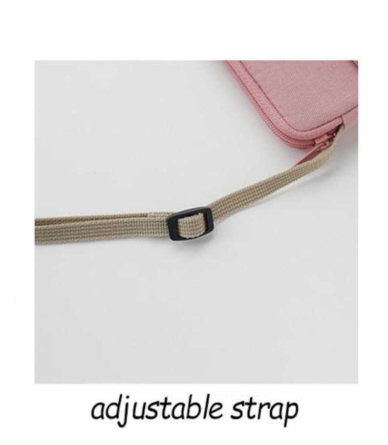 May include: A close-up of a light pink canvas bag with an adjustable strap. The strap is made of a beige fabric and has a black plastic buckle.