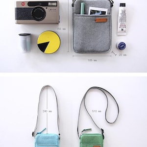 Puede incluir: Una colecci&oacute;n de accesorios que incluye un bolso bandolera gris (10,5 cm x 15,5 cm), un bolso bandolera azul claro (correa de 24 cm) y un bolso bandolera verde (correa de 51 cm). Tambi&eacute;n se muestra una c&aacute;mara, un cartucho de pel&iacute;cula y otros objetos peque&ntilde;os.