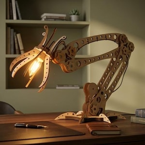 May include: A mechanical-style desk lamp constructed from laser-cut wood pieces. The lamp features an adjustable articulated arm with gear-like joints and a flower-shaped shade housing a single glowing light bulb, resting on a wide base.