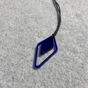 May include: A blue diamond-shaped pendant necklace with a black cord.