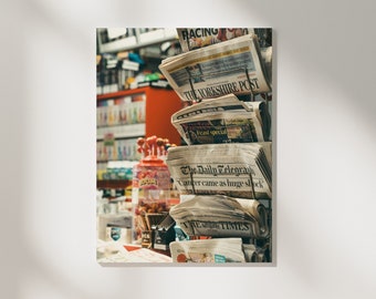 May include: A stack of newspapers on a metal rack. The top newspaper is titled "RACING" and the next one down is titled "THE YORKSHIRE POST". The newspaper below that is titled "The Daily Telegraph" with the headline "Cancer came as huge shock".