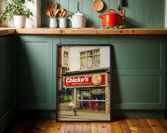 May include: A framed photograph of a storefront with a red sign that reads "Chicko's" in white letters. The sign also includes the words "chicken & pizza caribbean food". The storefront is located on a street with other buildings in the background.