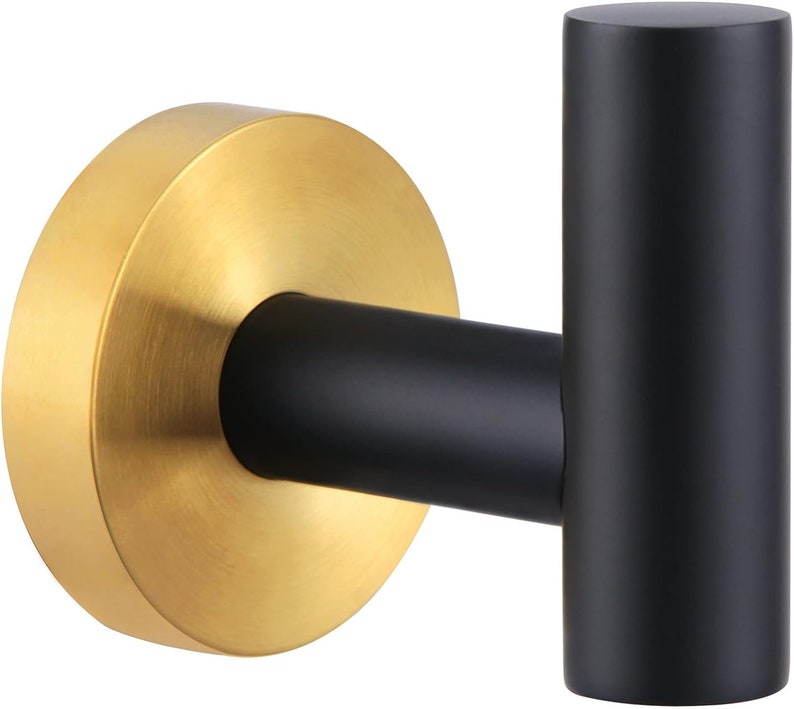 May include: A black and gold wall hook with a round base and a single hook. The hook is made of metal and has a brushed finish.