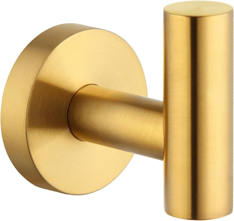 May include: Gold metal hook with a round base. The hook is designed for hanging items on a wall.