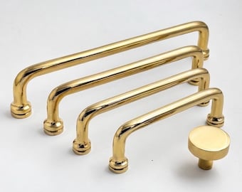 May include: A collection of four polished gold-toned metal drawer pulls of varying lengths, each featuring a smooth, rounded handle design with cylindrical mounting bases, accompanied by a single matching circular gold-toned cabinet knob.