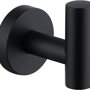 May include: A black metal hook with a round base. The hook is designed for hanging items on a wall.