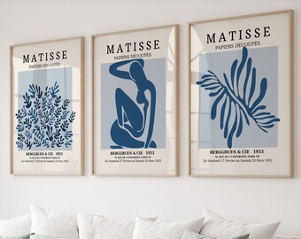May include: Three framed prints of Matisse's "Papiers Decoupes" artwork. The prints feature a blue and white color scheme and depict abstract shapes of leaves, a seated figure, and a stylized branch.