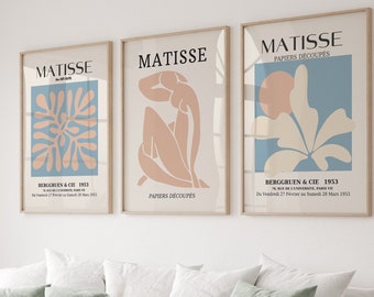 May include: Three framed art prints with a blue, beige, and white color scheme. The prints feature abstract shapes and the text "MATISSE PAPIERS DÉCOUPÉS" in black. The text below the prints reads "BERGGRUEN & CIE 1953 70, RUE DE L'UNIVERSITÉ, PARIS VIE Du Vendredi 27 Février au Samedi 28 Mars 1953."