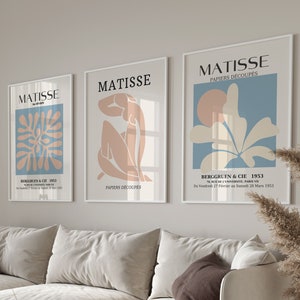 Pu&ograve; includere: Tre stampe d'arte incorniciate con il nome "MATISSE" e il titolo "PAPIERS D&Eacute;COUP&Eacute;S" in testo nero. Le stampe presentano disegni astratti in tonalit&agrave; di blu, rosa e bianco.
