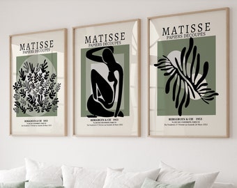 May include: Three framed prints with a green background and black cut-out designs. The prints feature the text "MATISSE PAPIERS DÉCOUPÉS" and the artist's signature. The designs include a cluster of leaves, a seated figure, and a single leaf.