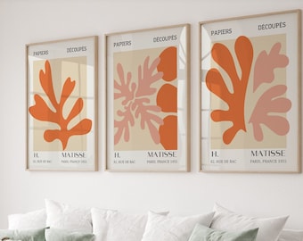 May include: Three framed prints with the title "PAPIERS DÉCOUPÉS" and the artist's name "H. MATISSE" along with the date "PARIS, FRANCE 1955". Each print features a different abstract design of orange and pink shapes.