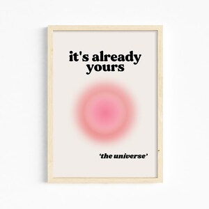 May include: A framed print with a pink and white gradient circle in the center. The text "it's already yours" is above the circle and "'the universe'" is below the circle.