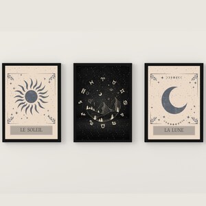 May include: Three framed prints with a celestial theme. The first print features a sun with rays, the second print features a crescent moon with stars and zodiac symbols, and the third print features a crescent moon with stars. The prints are all in black frames with a cream background.