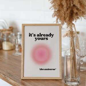 May include: A framed print with a pink and white gradient circle and the text "it's already yours 'the universe'".