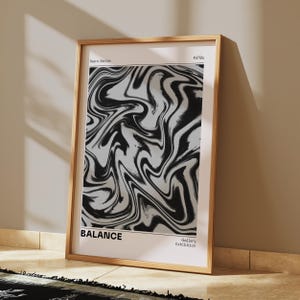 May include: Wooden framed art print featuring a black and white abstract design with swirling patterns. The print is labeled "Balance" and "Retro Series" with "Gallery Exhibition" text. The frame is a light brown color, and the artwork leans against a wall.