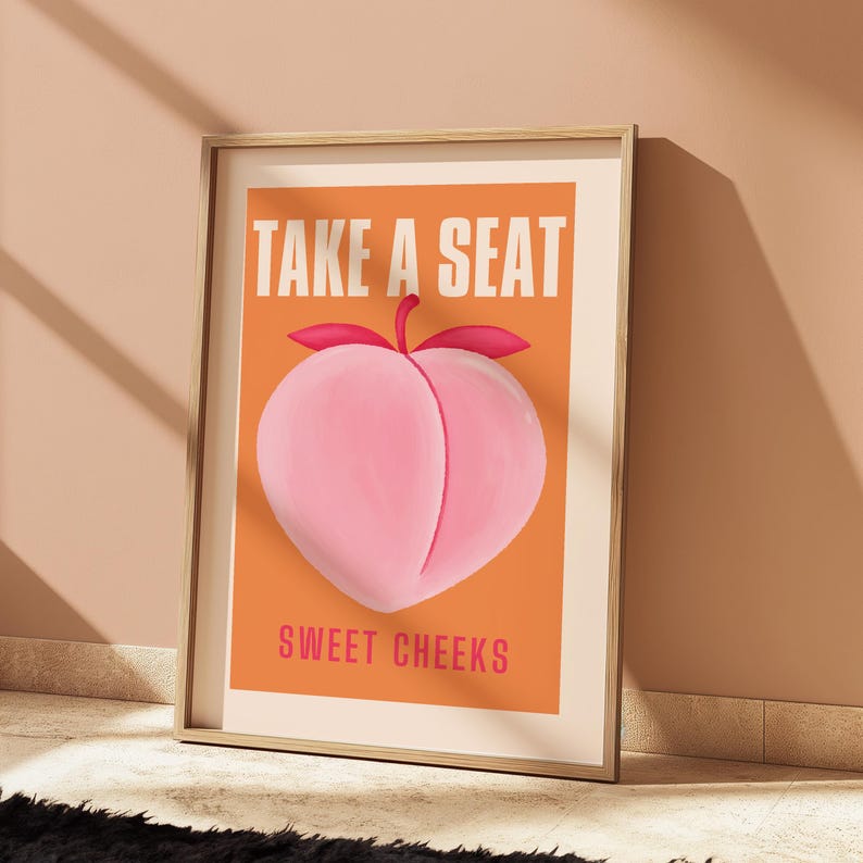 May include: A peach-colored poster with the text "Take a Seat" in white letters and "Sweet Cheeks" in white letters below a peach illustration.