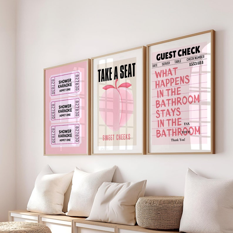 May include: Three framed prints with pink and white designs. The left print has a pink ticket with the text "Shower Karaoke Admit One" repeated three times. The middle print has a peach with a pink background and the text "Take a Seat Sweet Cheeks". The right print has a pink and white grid with the text "Guest Check Date Server Table Check Number 1533484 What Happens in the Bathroom Stays in the Bathroom Tax Total Thank You!"