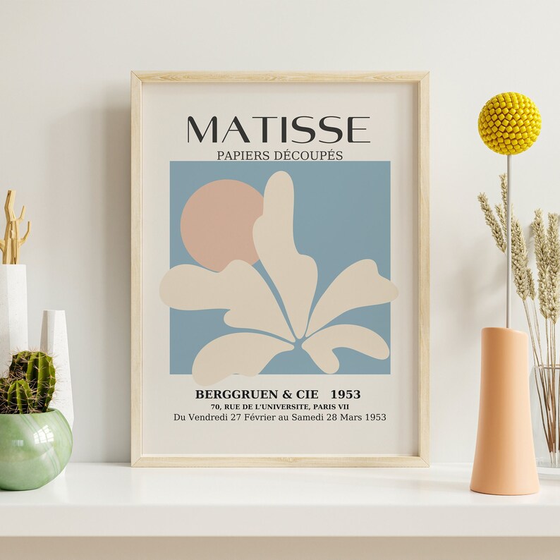 Pu&ograve; includere: Una stampa incorniciata di un'opera d'arte di Matisse intitolata "PAPIERS D&Eacute;COUP&Eacute;S". L'opera d'arte presenta un fiore stilizzato con un cerchio rosa sullo sfondo. Il testo "BERGGRUEN & CIE 1953" &egrave; nella parte inferiore della stampa, insieme all'indirizzo "70, RUE DE L'UNIVERSITE, PARIS VII" e alle date "Du Vendredi 27 F&eacute;vrier au Samedi 28 Mars 1953".