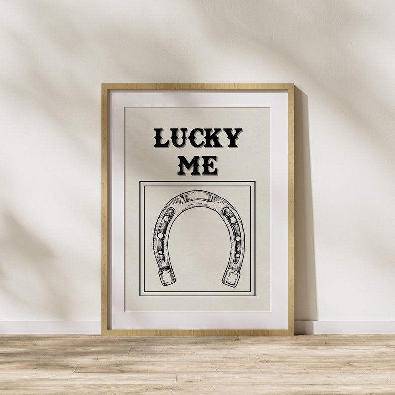 May include: A framed print with the text "LUCKY ME" and a black and white illustration of a horseshoe.