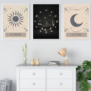 May include: Three framed prints with a celestial theme. The first print features a sun with the text "LE SOLEIL". The second print features a mountain range with stars and zodiac symbols. The third print features a crescent moon with the text "LA LUNE".