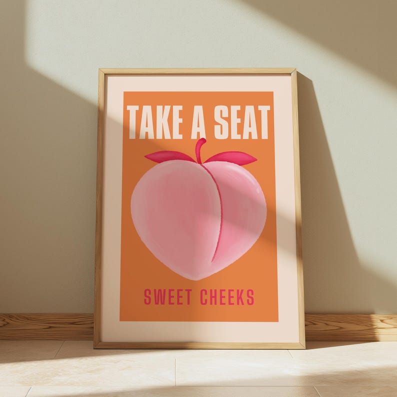 May include: A peach-colored poster with the text "TAKE A SEAT" in white letters and "SWEET CHEEKS" in white letters below a cartoon peach.