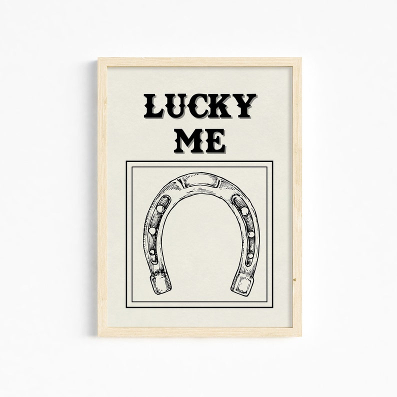 May include: A framed print with a black and white illustration of a horseshoe and the text "LUCKY ME" in black.