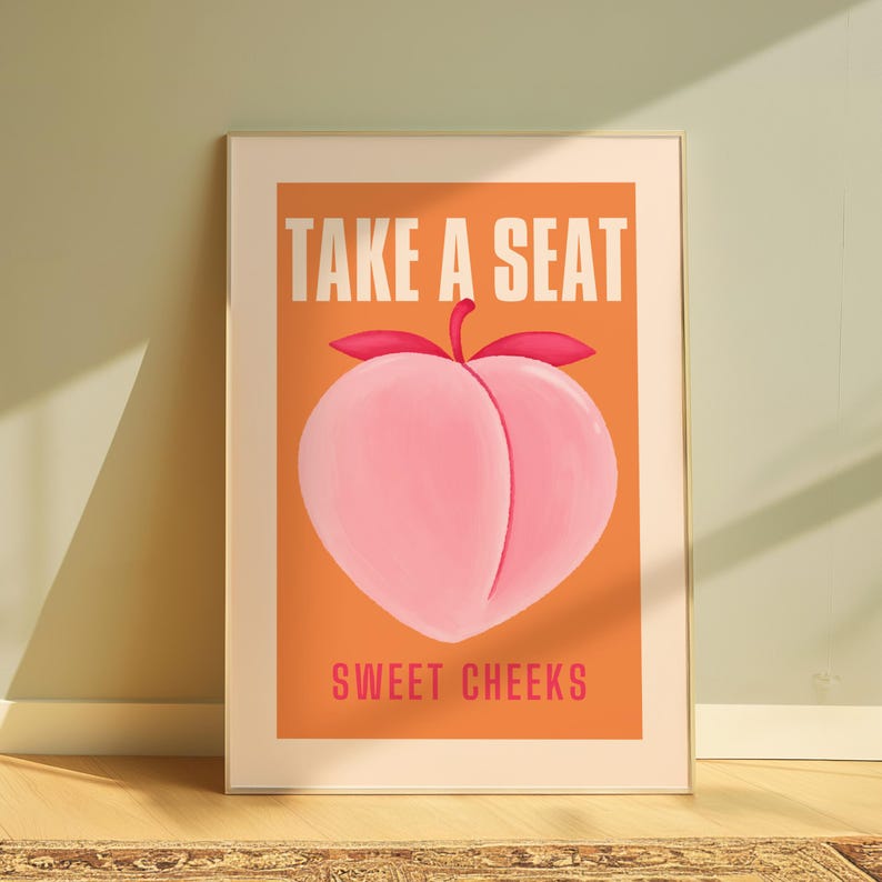 May include: A peach-colored poster with the text "Take a Seat" in white letters and "Sweet Cheeks" in pink letters. The poster features a stylized peach with a pink and red color scheme.