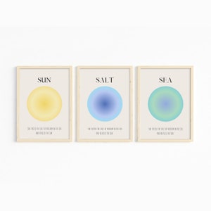 May include: Three framed prints with a minimalist design. Each print features a circle with a gradient color scheme. The top of each print has a word in black text: "SUN", "SALT", and "SEA". The bottom of each print has the same text in smaller font: "She tasted the salt of freedom in the sea and revealed the sun."
