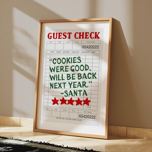 May include: A white framed print with a red and green guest check that reads "COOKIES WERE GOOD, WILL BE BACK NEXT YEAR." -SANTA with five red stars below the text. The check number is 65420222.