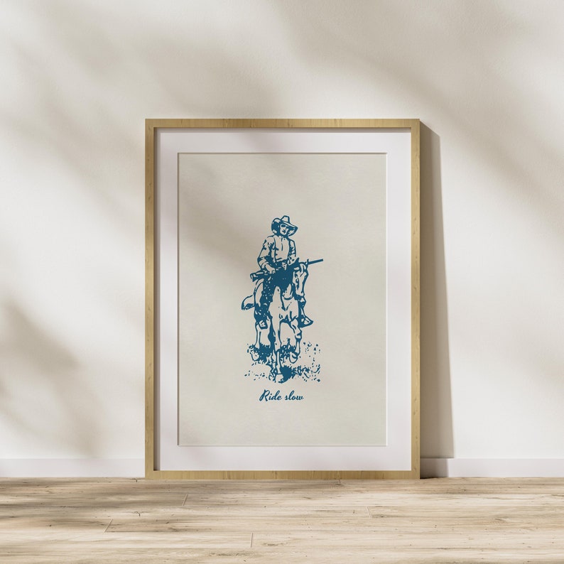 May include: A framed print with a blue illustration of a cowboy riding a horse. The text "Ride slow" is printed below the illustration.