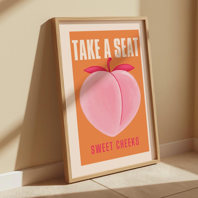 May include: A peach-colored poster with a peach illustration and the text "Take a Seat Sweet Cheeks" in white and pink lettering.